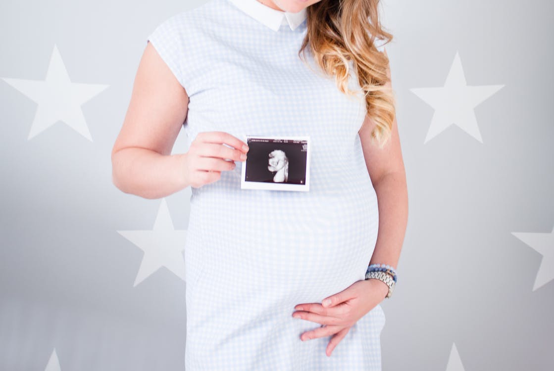 A pregnant woman holding a picture of a fetus